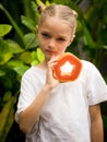 Charming little girl with fresh papaya. Caucasian girl holding slice of papaya fruit in front of her neck. Selected focus. Green Royalty Free Stock Photo