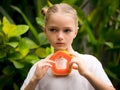 Charming little girl with fresh papaya. Caucasian girl holding slice of papaya fruit in front of her neck. Selected focus. Green
