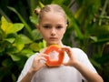 Charming little girl with fresh papaya. Caucasian girl holding slice of papaya fruit in front of her neck. Selected focus. Green Royalty Free Stock Photo