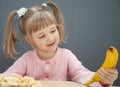 Charming little girl holding a ripe banana