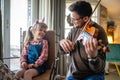 Charming little girl learning to play the violin with an artistic music teacher. Royalty Free Stock Photo