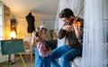 Charming little girl learning to play the violin with an artistic music teacher.