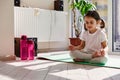 Charming little girl during meditation and yoga practice in lotus position on a fitness mat at home. Serenity, relaxation concept