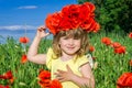 Charming little girl in a poppy field with a bouquet of poppies on her head Royalty Free Stock Photo