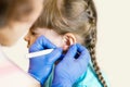 A charming little girl is undergoing the procedure of ear piercing by a professional medical worker. Adorable little girl having Royalty Free Stock Photo