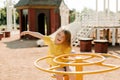 A charming little girl is walking in the park, swinging on a swing. Happy childhood, playtime Royalty Free Stock Photo