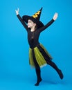 charming little girl in a witch costume dancing in the studio on a blue background Royalty Free Stock Photo