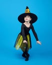 charming little girl in a witch costume dancing in the studio on a blue background Royalty Free Stock Photo