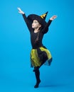 charming little girl in a witch costume dancing in the studio on a blue background Royalty Free Stock Photo