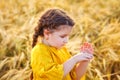 A charming little girl in a yellow dress with a ladybug in the middle of a wheat field. Photo with backlight  soft focus Royalty Free Stock Photo