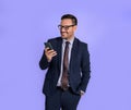 Charming male business professional with hand in pocket checking messages over smart phone. Young entrepreneur dressed in formals Royalty Free Stock Photo