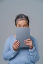 Charming mature grey haired woman hide shy behind digital tablet working or shopping online or checking on social media Royalty Free Stock Photo