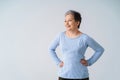 Charming mature silver, grey hair woman posing with hands on her hips looking sideways away wearing blue blouse Royalty Free Stock Photo