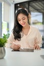 Charming millennial Asian businesswoman using digital tablet at her desk in the office Royalty Free Stock Photo