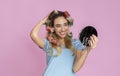 Charming millennial girl with curlers holds mirror