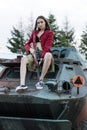 Charming model with the gun sitting on the tank. Royalty Free Stock Photo