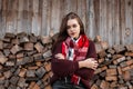 Charming model of a pretty young woman in a stylish knitted sweater with a fashionable scarf stands near an old wooden wall with Royalty Free Stock Photo