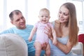 Charming mom holding baby while sitting with dad on sofa Royalty Free Stock Photo