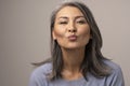 Charming Mongolian Woman with Gray Hair Over a Gray Background.