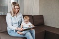 Charming mother showing images in a book to her cute little son at home sitting on the couch Royalty Free Stock Photo