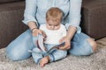 Charming mother showing images in a book to her cute little son at home sitting on the floor Royalty Free Stock Photo