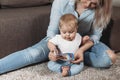 Charming mother showing images in a book to her cute little son at home sitting on the floor Royalty Free Stock Photo