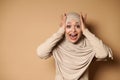 A charming muslim woman in hijab and strict clothes holds her head with both hands and looks at the camera in surprise