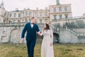 Charming newlywed bride and groom walking near beautiful ruined baroque palace Royalty Free Stock Photo