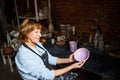 Charming old woman holding painted bowl in pottery workshop Royalty Free Stock Photo