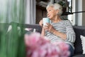 Charming old woman relaxing on couch with hot drink Royalty Free Stock Photo