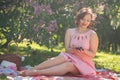 Charming pinup girl enjoys a rest and a picnic on the green summer grass. pretty vintage style caucasian woman spend vacantion on