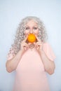 Charming plump curly blonde in pink dress with orange on white solid studio background alone