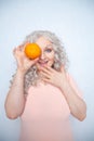 Charming plump curly blonde in pink dress with orange on white solid studio background alone