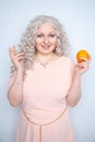 Charming plump curly blonde in pink dress with orange on white solid studio background alone