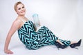 Charming plus size young woman in black blue jumpsuit with glass of water on white background in Studio. pretty blonde girl wearin Royalty Free Stock Photo