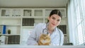 portrait of a beautiful asian female veterinarian with cat on diagnosis table at clinic