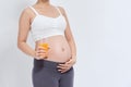 Charming pregnant woman holding a glass of orange juice while standing