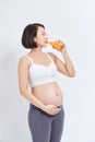 Charming pregnant woman holding a glass of orange juice while standing