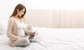 Charming pregnant woman relaxing with her laptop on bed Royalty Free Stock Photo