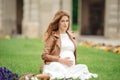 Charming pregnant woman relaxing in the park