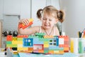 Charming preschooler playing with doll house constructor. Little girl playing with connecting toy cubes Royalty Free Stock Photo