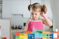 Charming preschooler playing with doll house constructor. Little girl playing with connecting toy cubes Royalty Free Stock Photo