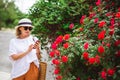 Beautiful, adult woman in hat and glasses in park typing message surfing Internet, doing online shopping in smartphone.