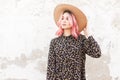 Charming pretty young woman with luxurious pink hair in stylish black floral dress straightens vintage beautiful straw hat near Royalty Free Stock Photo