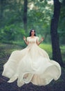 Charming princess in a bright green forest dances alone, dark-haired girl in long white elegant gentle dress with flying