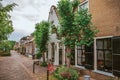 Charming and quiet street with brick rustic houses and greenery in cloudy day at Drimmelen. Royalty Free Stock Photo