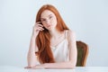 Charming redhead woman sitting at the table