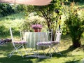 Charming relaxation area in a garden, in the shade of a stretched canvas and flowers on the table