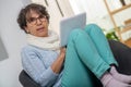 Charming senior brunette woman with glasses using digital tablet at home Royalty Free Stock Photo