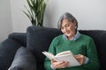 Charming senior lady reading a book on the sofa Royalty Free Stock Photo